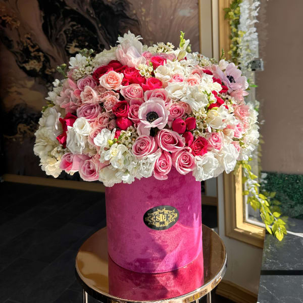 Pink and white rose arrangement in a velvet hat box