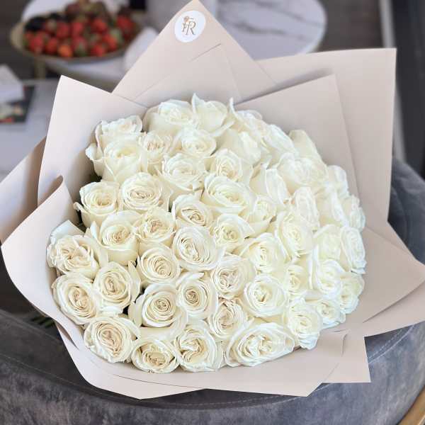 Bouquet of white roses wrapped in pale beige paper