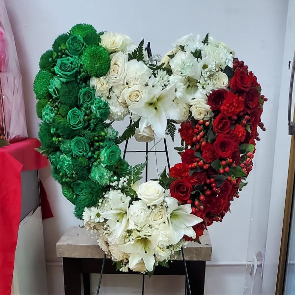 Heart-shaped floral arrangement in green, white, and red roses with lilies