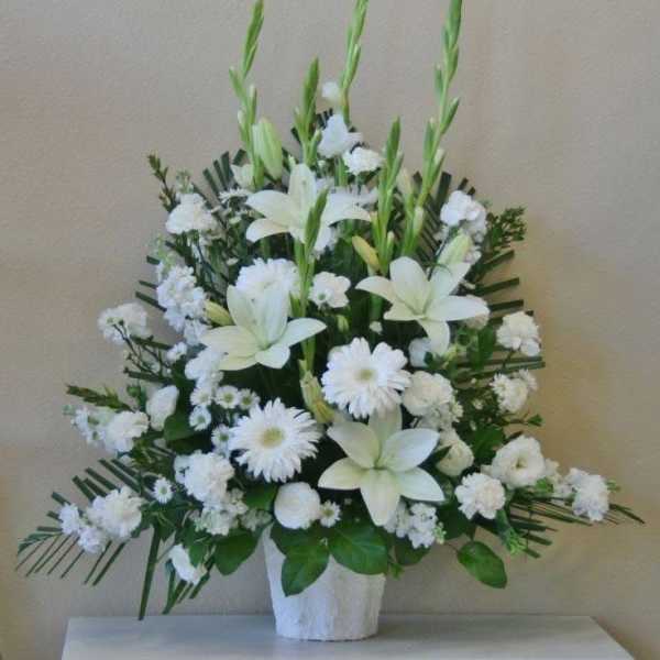 White lilies and daisies arranged in a white vase