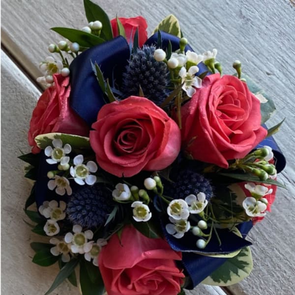Bouquet of pink roses with white filler flowers and dark blue ribbon