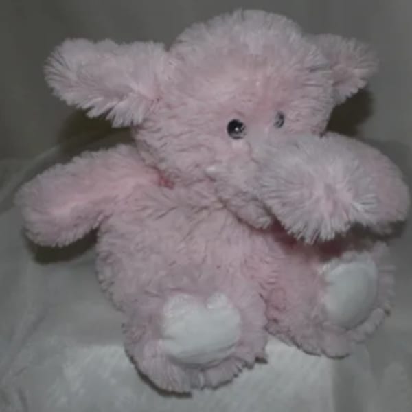 Pink plush teddy bear with white paws and black eyes