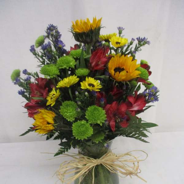 Mixed bouquet in a glass vase with bright yellow, red, green, and purple flowers