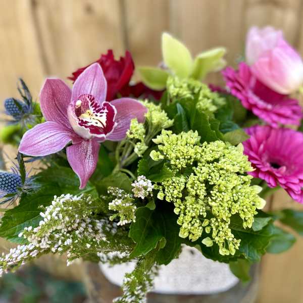 Mixed bouquet with pink orchids, magenta blooms, and green hydrangea in a vase