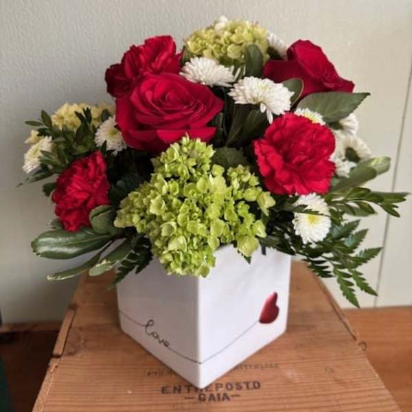 Bouquet of red roses, carnations, white daisies, and green hydrangea in a white box