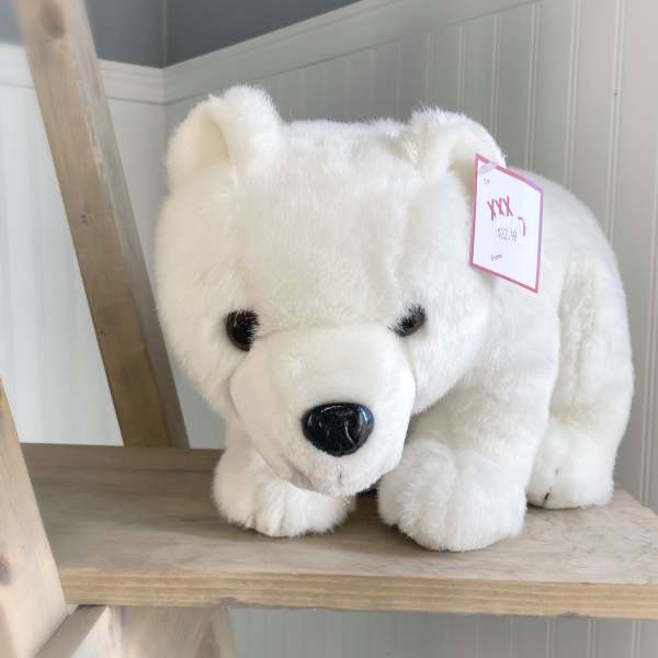 White plush polar bear with a price tag on a wooden shelf