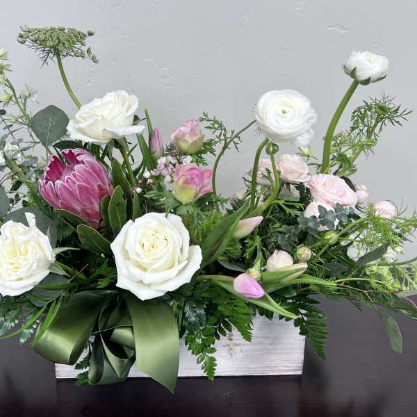 White and pink floral arrangement in a white box with a green ribbon