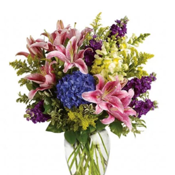 Pink lilies and purple flowers in a clear glass vase