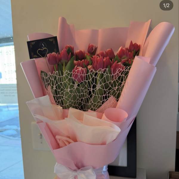 Pink tulip bouquet wrapped in pastel paper with a white ribbon