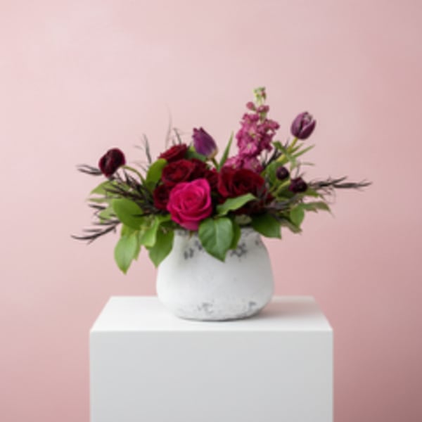 Pink and burgundy flower arrangement in a white vase