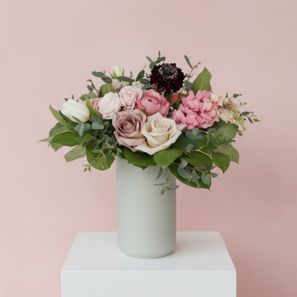 Pink and white rose bouquet in a tall pale vase
