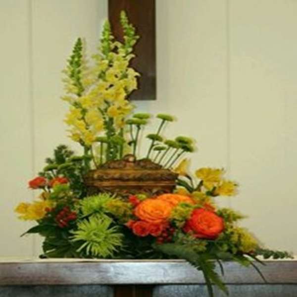 Tall floral arrangement with orange and yellow blooms in a basket