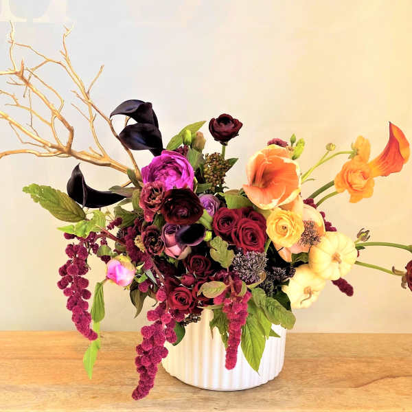 Mixed floral arrangement in a white vase with branches and dark blooms