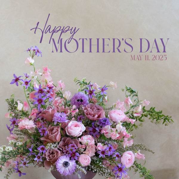 Pink and purple floral arrangement in a lavender pedestal vase