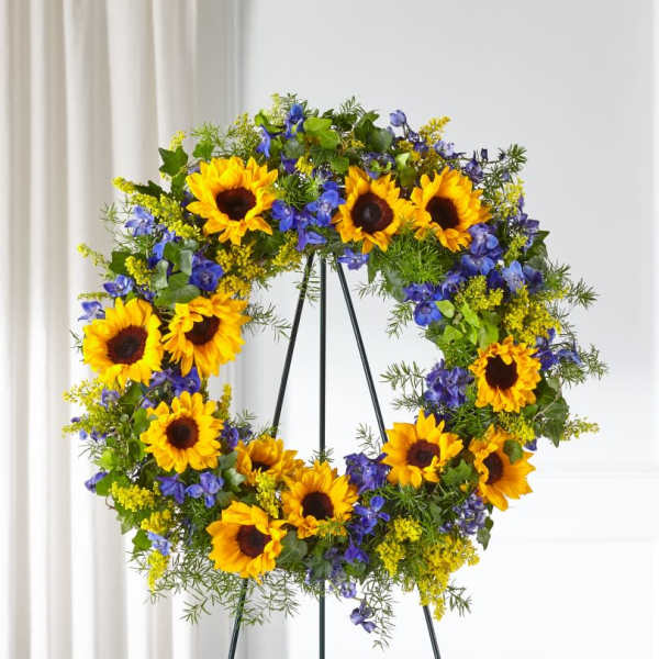 Sunflower wreath with blue flowers on a black stand
