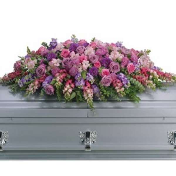 Pink and purple floral casket spray on a gray casket