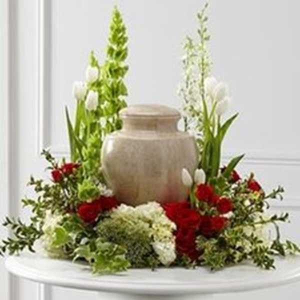 Red and white floral arrangement around a beige urn