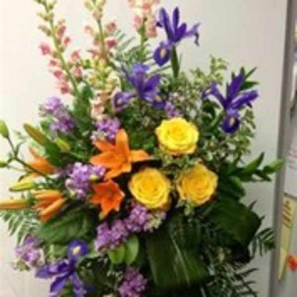 Tall standing floral spray with yellow roses, purple irises, and orange lilies