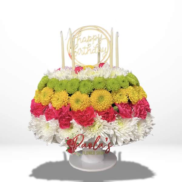 Tiered birthday cake made of colorful flowers with candles and a topper