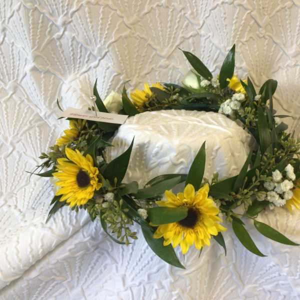 Sunflower wreath around a white cake on a textured cloth