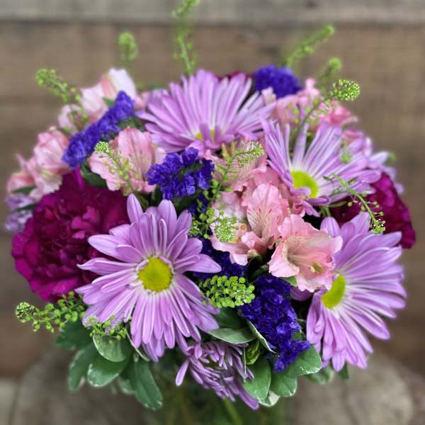Bouquet of lavender daisies and pink alstroemeria in a glass vase