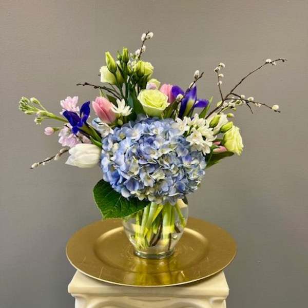 Blue hydrangea bouquet with tulips and irises in a glass vase