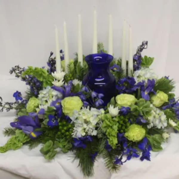 Blue and green floral centerpiece with tall white candles and a cobalt vase