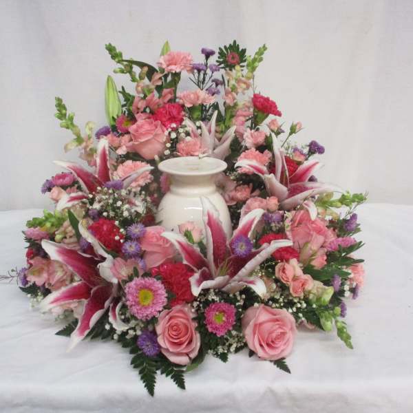 Pink and purple floral arrangement around a white urn