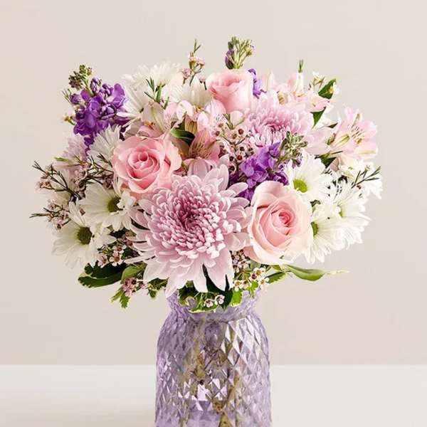 Pink and white mixed bouquet in a purple glass vase