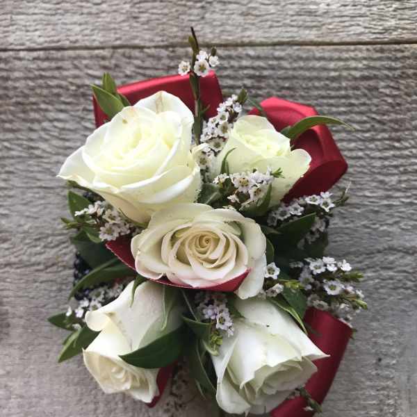 White rose bouquet with small white filler flowers and red ribbon