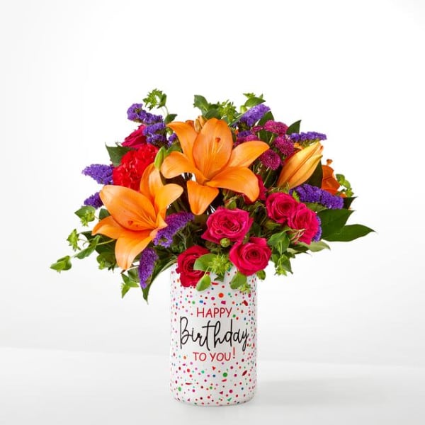 Bouquet of orange lilies and pink roses in a birthday vase