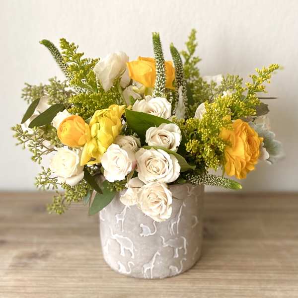 Yellow and white roses arranged in a patterned ceramic vase