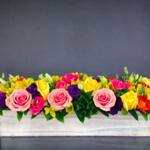Long rectangular flower arrangement with pink, yellow, purple, and orange blooms in a white box