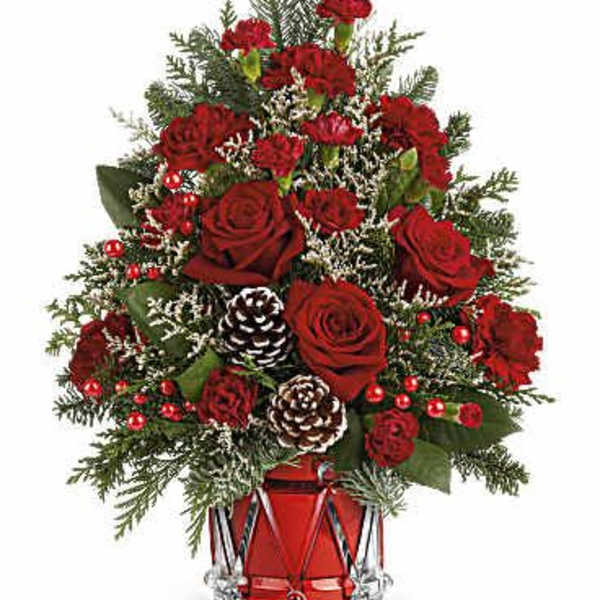 Red roses and carnations in a glass vase with pinecones and evergreen accents