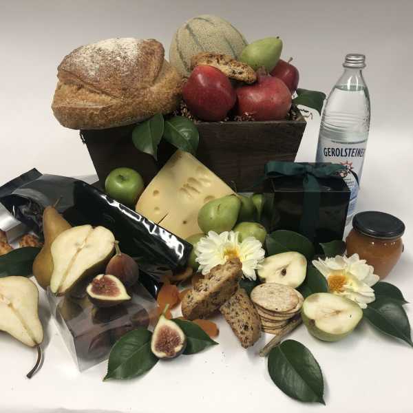 Gift basket with bread, fruit, cheese, cookies, flowers, and a bottle of sparkling water