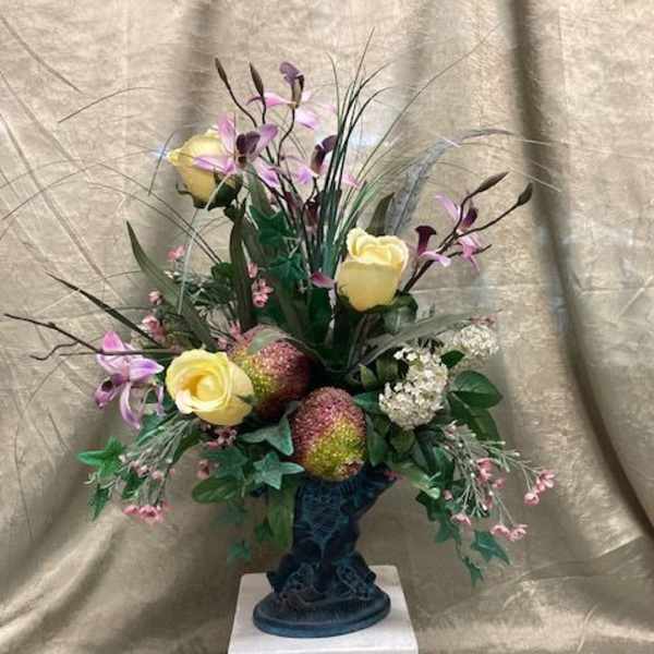 Tall floral arrangement with yellow roses and purple orchids in a dark vase