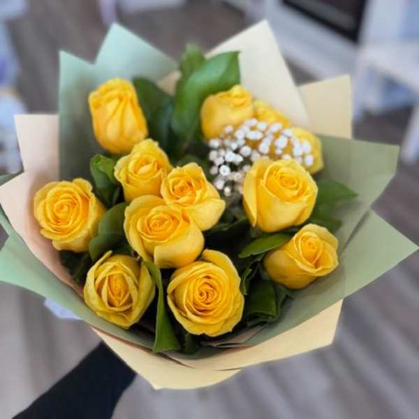 Bouquet of yellow roses wrapped in pastel paper