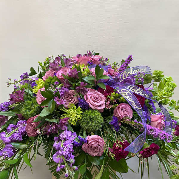 Large purple and pink floral spray with ribbon on a stand