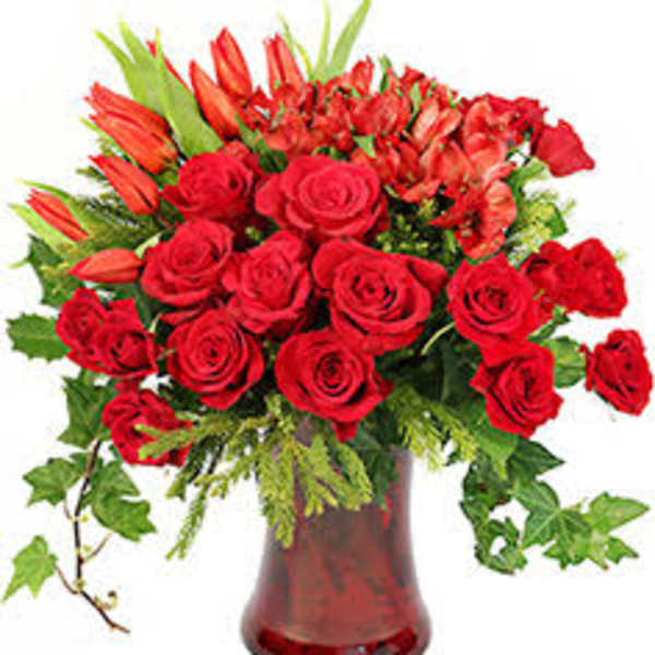 Red roses and orange lilies in a red glass vase