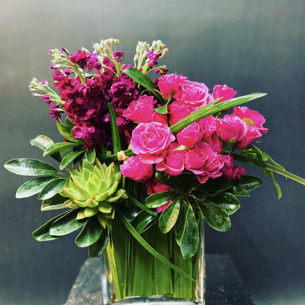 Pink roses and dark magenta flowers in a clear glass vase