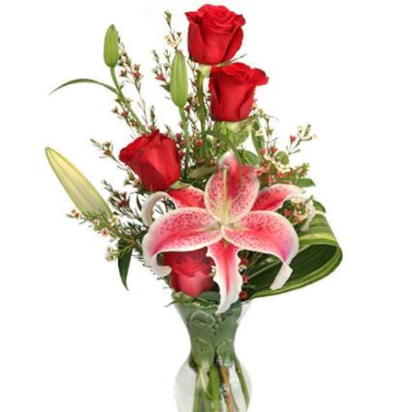 Red roses and a pink stargazer lily in a clear glass vase