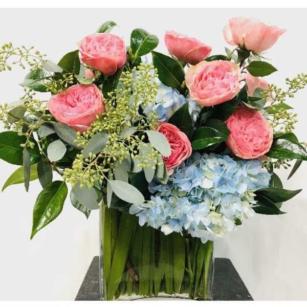 Pink roses and blue hydrangeas in a clear glass vase