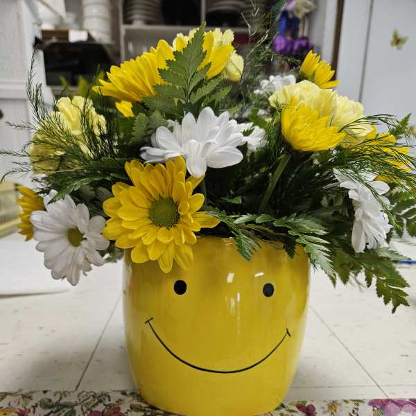 Yellow and white daisies in a smiley-face yellow pot
