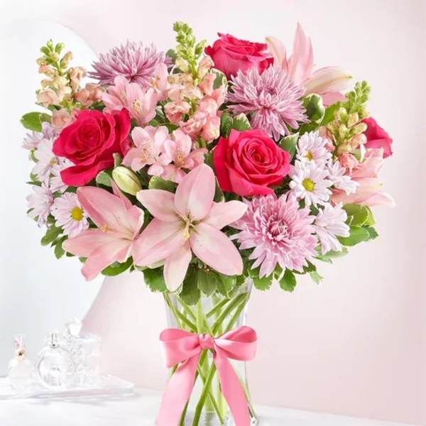Pink and white mixed bouquet in a glass vase with a pink ribbon