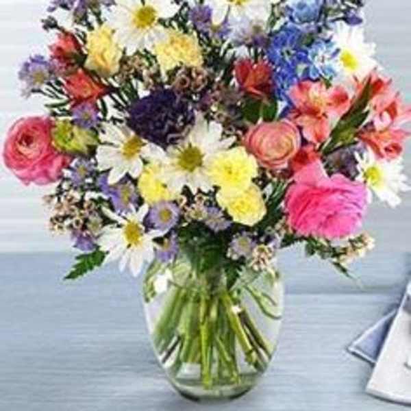 Mixed bouquet of daisies, roses, and colorful blooms in a glass vase