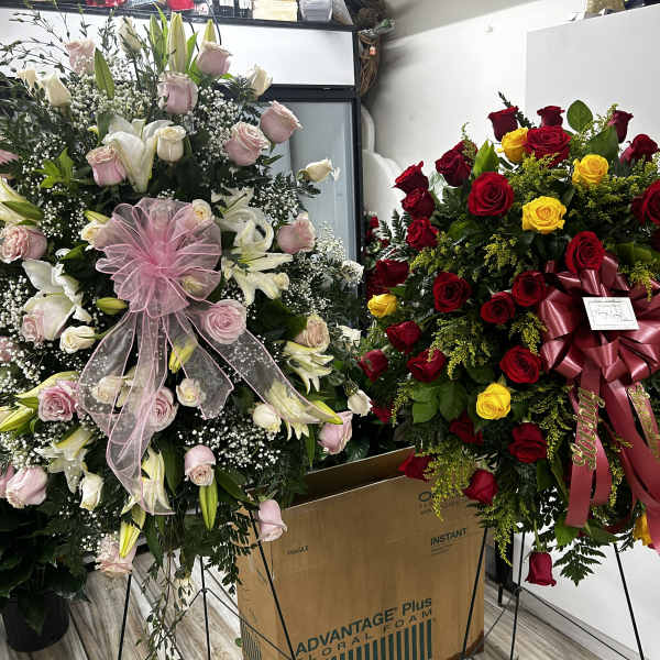 Two large standing floral wreaths, one pink and white and one red and yellow
