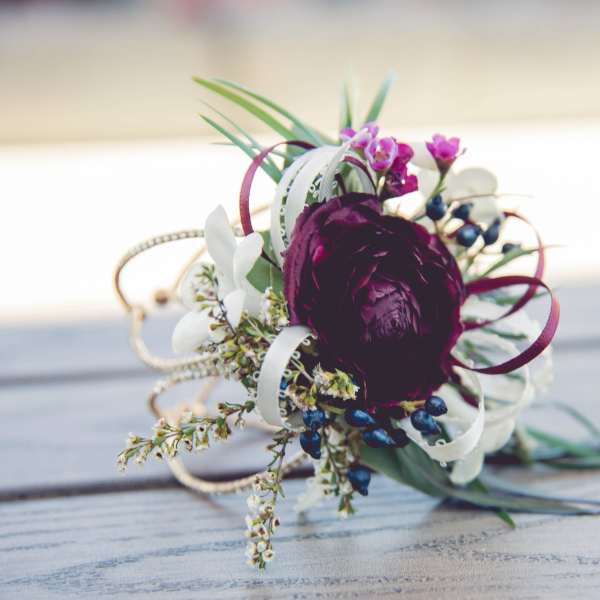 Small floral corsage with a dark purple bloom and white accents
