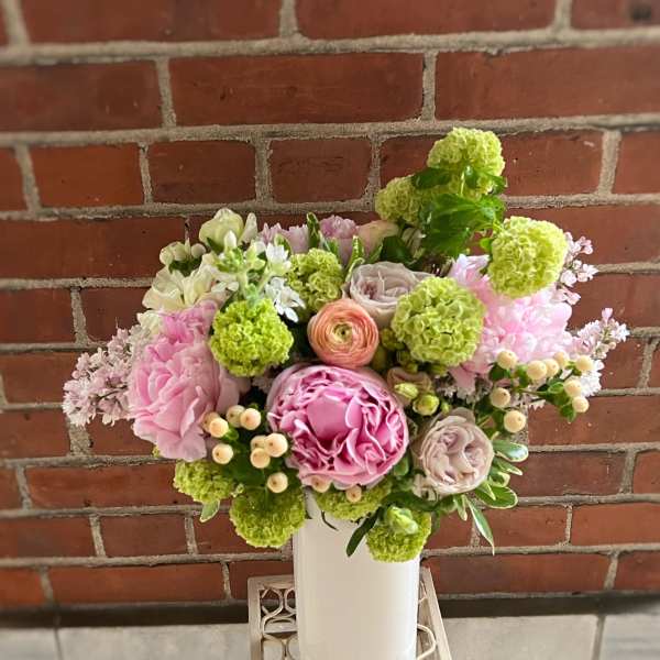 Pink and green floral arrangement in a white vase