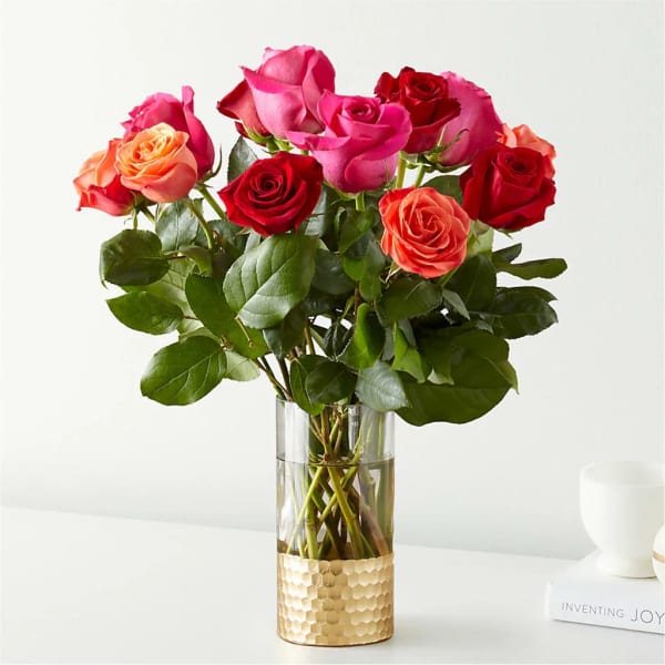 Bouquet of pink, red, and peach roses in a clear glass vase