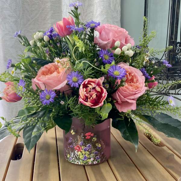 Pink roses and tulips with purple daisies in a decorative vase